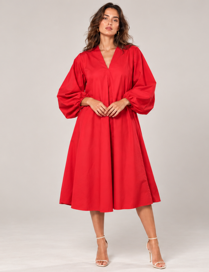 Woman wearing the Lili Dress sewing pattern in red, featuring a V-neckline, relaxed silhouette and voluminous puff sleeves