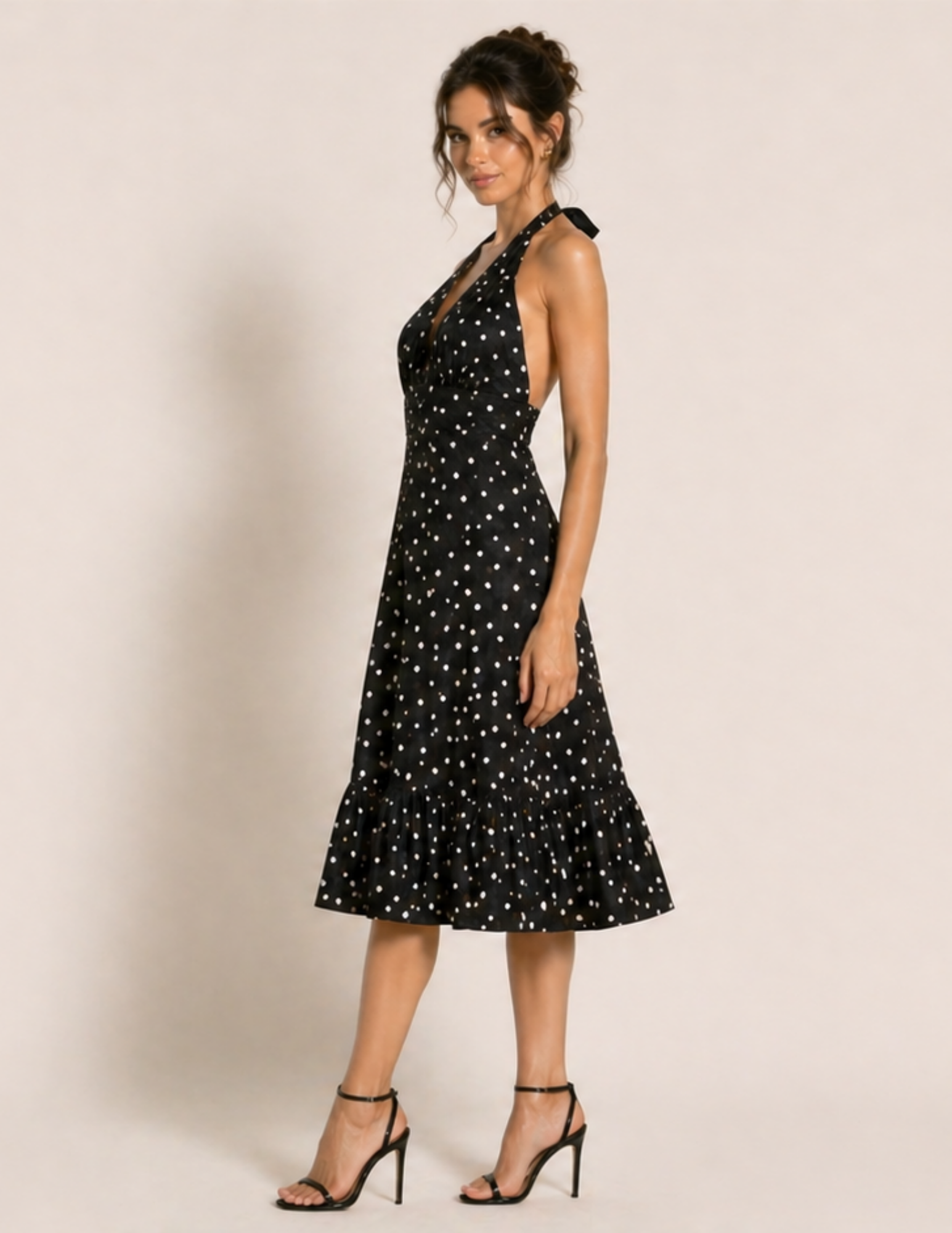 Woman wearing a black dress with white polka dots against a plain background