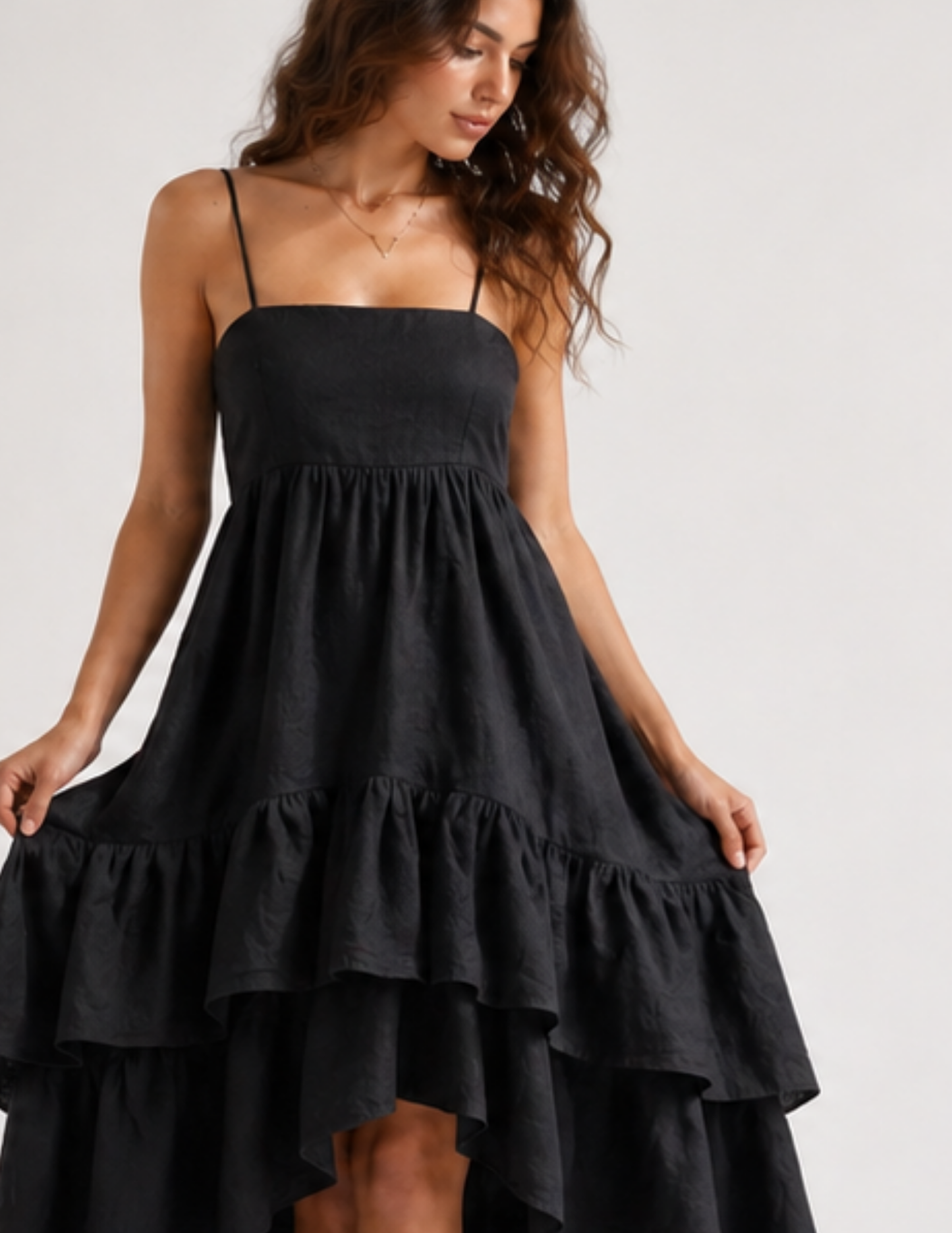 Woman wearing a black tiered dress on a plain background