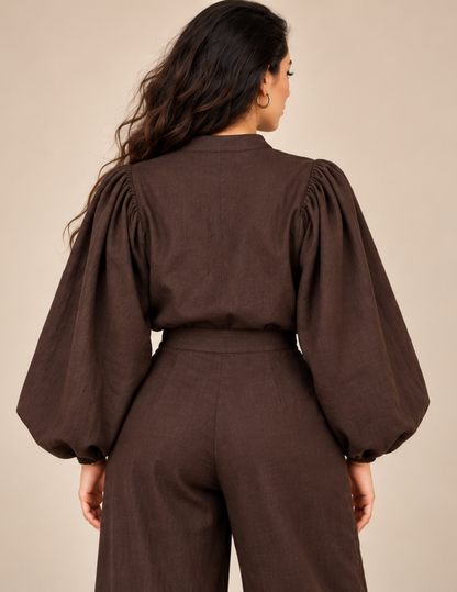 Back view of a brown women's puff sleeve blouse showing the gathered 
shoulders, voluminous kimono-style sleeves, mandarin collar, relaxed back and 
elasticated sleeve cuffs.