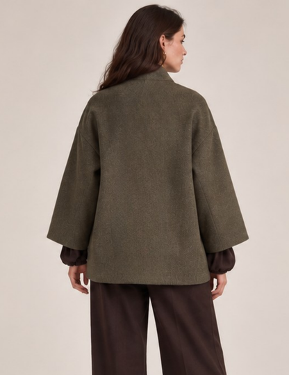 Back view of the MILDA oversized wrap coat sewing pattern showing the relaxed straight silhouette, wide sleeves, shawl collar, and olive green textured fabric