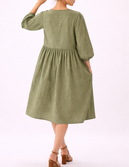 MIMA dress sewing pattern shown from the back, featuring a gathered skirt, long puff sleeves and a relaxed midi silhouette in sage green linen