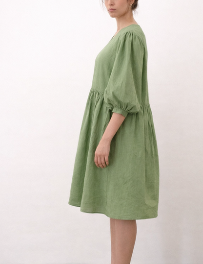 Close-up of the MIMA dress sewing pattern showing gathered puff sleeves, elastic cuffs and V-neck detail in sage green fabric