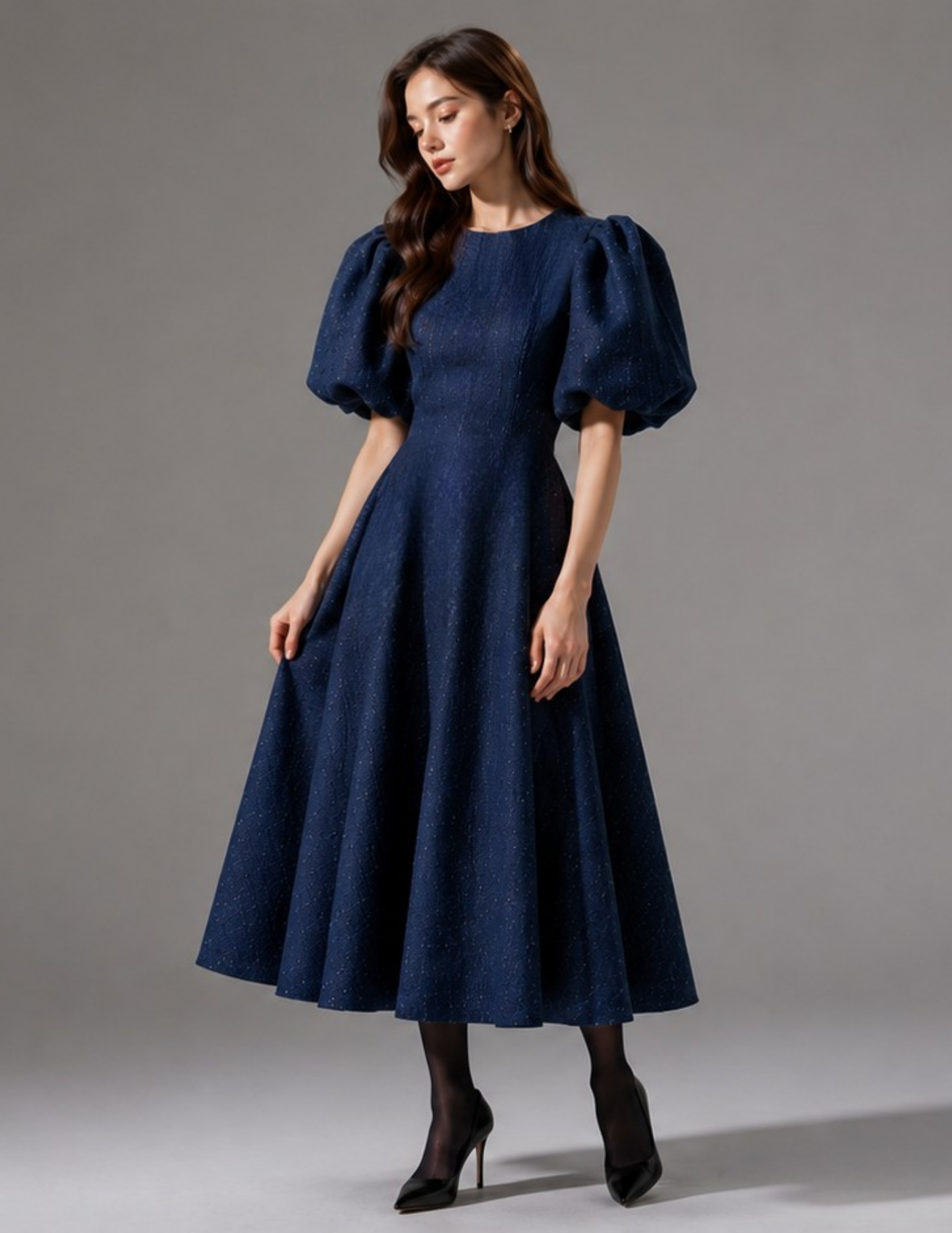 Woman wearing the OLGA dress, a navy blue puff sleeve fit and flare midi dress sewing pattern