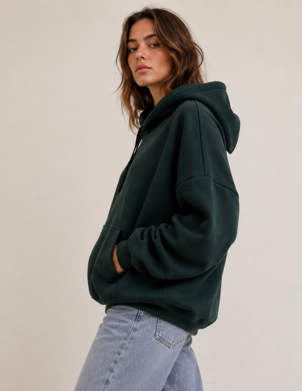 Side view of the VERNA women's 
pullover hoodie showing the relaxed 
silhouette, dropped shoulder, long 
sleeve, hood, and kangaroo pocket