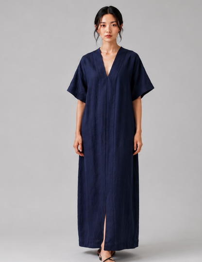 A woman modeling a navy blue, short-sleeved maxi dress with a V-neckline and front slit, photographed against a neutral gray studio background.
Women's V-neck dress sewing pattern 
shown from the front with loose fit, 
short sleeves and long straight 
silhouett